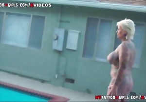 Tall tattooed blonde with big boobs poses by the poolside